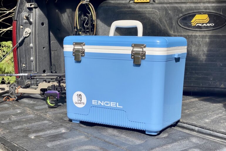 This review photo shows the Engel 19 Quart Drybox/Cooler on the tailgate of a pickup truck out in a forest during the real-world testing process.