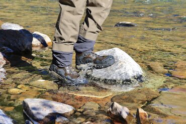 This review photo shows the author wearing the Grundens Bankside Wading Boots in a river during the fly fishing test and review process.