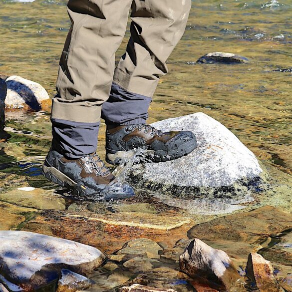 This review photo shows the author wearing the Grundens Bankside Wading Boots in a river during the fly fishing test and review process.