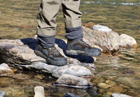 This review photo shows the author wearing the Grundens Bankside Wading Boots in a river with the Grundens Bondary Stockingfoot Waders during the testing and review process.