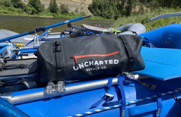 This photo shows the Uncharted Supply Co The Vault 65L Duffel on a whitewater raft.