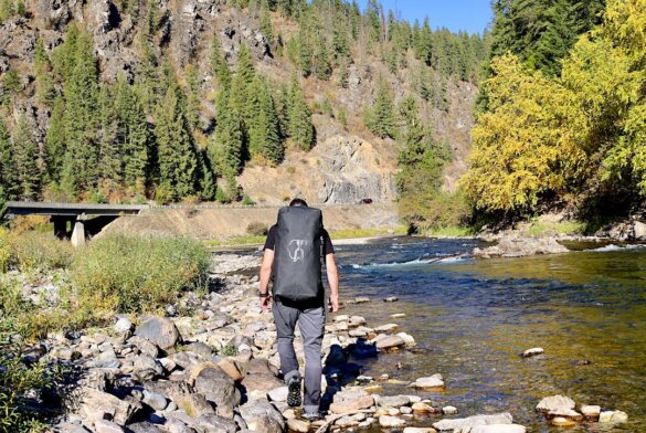 This photo shows the author carrying The Vault 65L Duffel in backpack mode while he walks near a mountain river in Idaho.