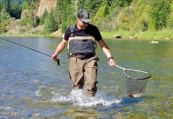 This photo shows the author testing the Grundens Boundary Stockingfoot Waders while wading in a river while fly fishing.