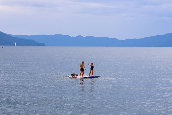 This photo shows three people playing on an inflatable dock on a mountain lake in Idaho during the testing and review process for this floating inflatable dock buying guide.
