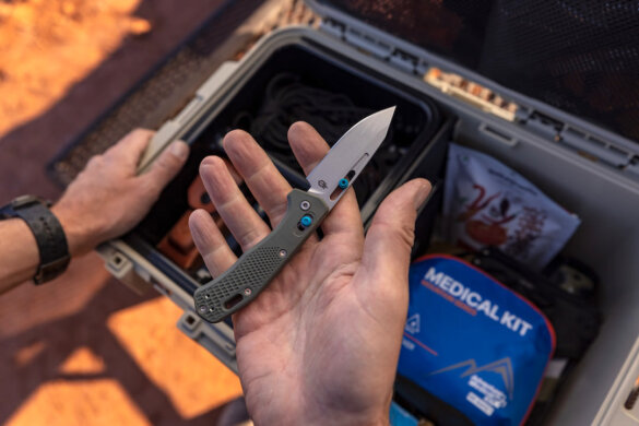 Man holding Gerber Gear Assert knife above a camping gear box.