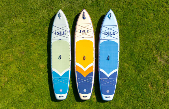 Three ISLE Explorer 3 inflatable standup paddle boards side-by-side on green grass.
