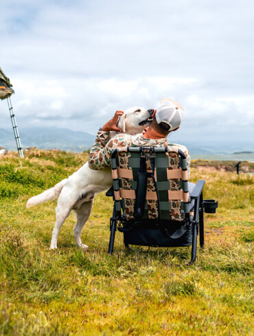 Man sitting in a camp chair in an off-grid camping location with a dog.