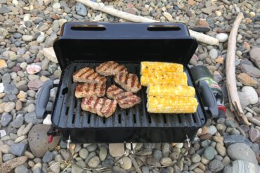 Weber Go Anywhere Gas Grill with grilled steak and corn on the cob.
