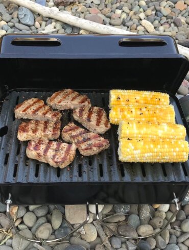 Weber Go Anywhere Gas Grill with grilled steak and corn on the cob.