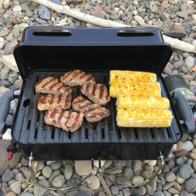 Weber Go Anywhere Gas Grill with grilled steak and corn on the cob.