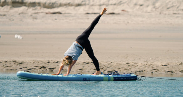Woman doing yoga on an ISLE Pioneer 3 inflatable stand-up paddle board on the a lake.