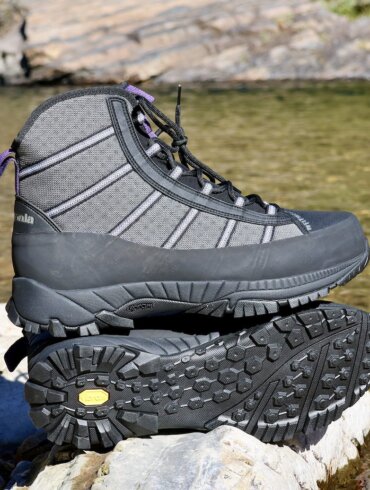 Pair of lightweight wading boots on a rock by a river.
