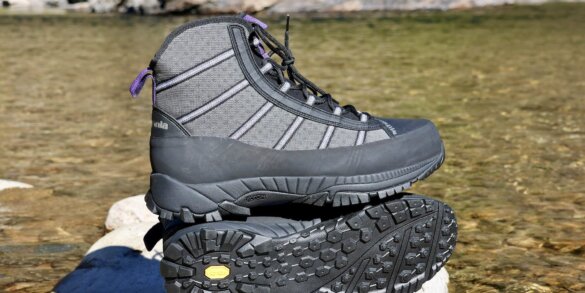 Pair of lightweight wading boots on a rock by a river.