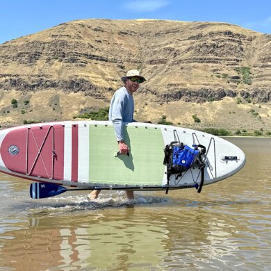 Author Chris Maxcer carries the ISLE Pioneer 3 Paddle Board in the water during the testing and review process.