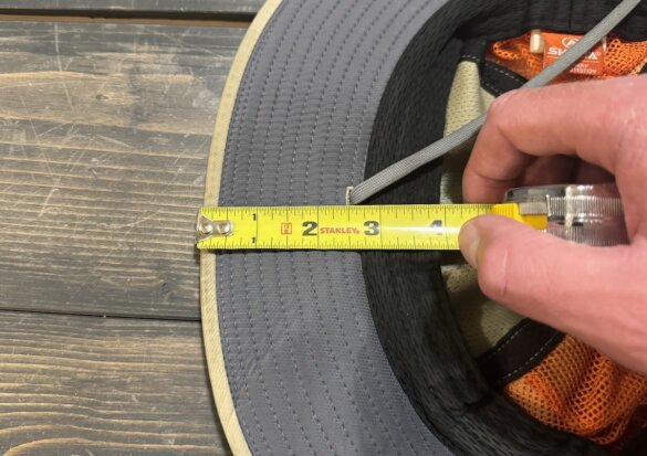 The author measures the brim width on a Shelta hat with a tape measure.