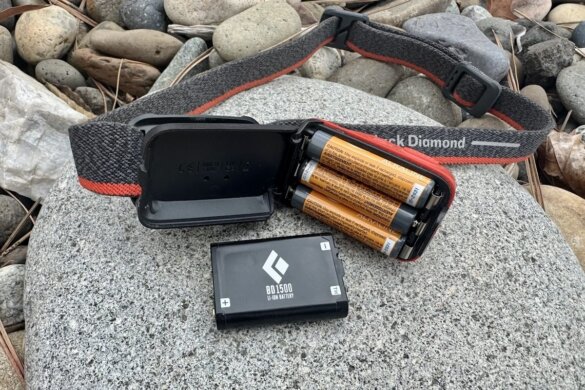 Spot 400 headlamp shown with 3 AAA batteries installed with the door open next to the BD 1500 rechargeable battery.