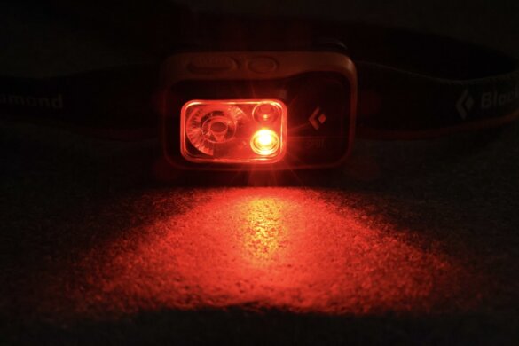 Headlamp shown with red light mode turned on in a dark environment. 