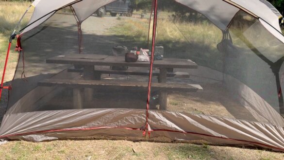 Closeup of picnic table inside of a mesh screen tent shelter.