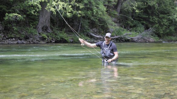 Fly fisherman Chris Maxcer tests wading gear while fly fishing in a mountain river for trout.