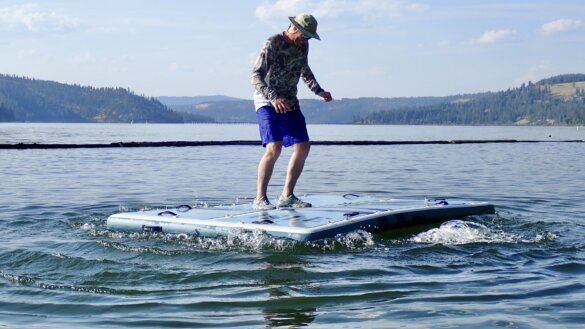 The author stands on an inflatable dock on a lake while testing stability on the water.