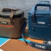 The RTIC 30-can and 20-can Ultra-Tough Soft Cooler side-by-side on an iSUP paddleboard on a beach near water.