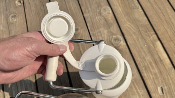 The author shows the cap and lid of the 1/2 gallon RTIC Outback Jug. 
