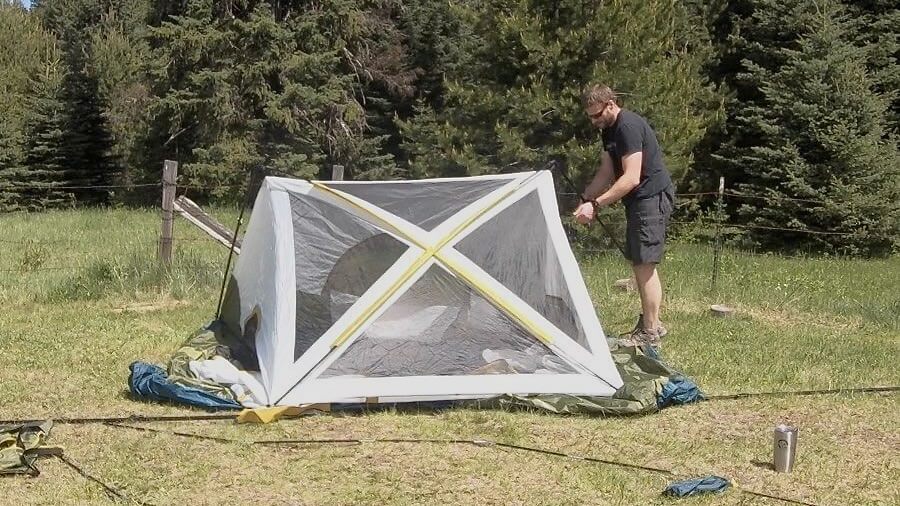 The author inserts poles into the corners of the L.L.Bean Acadia 6-Person Family Tent while pitching the tent in a meadow camping spot.