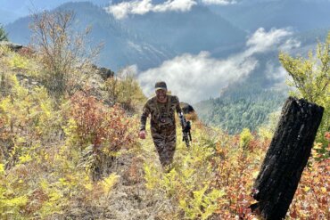 The author climbs a hill while carrying his bow while elk hunting in the mountains of Idaho.
