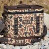 A YETI Hopper Flip 28 Soft Cooler on a rocky lake shore.