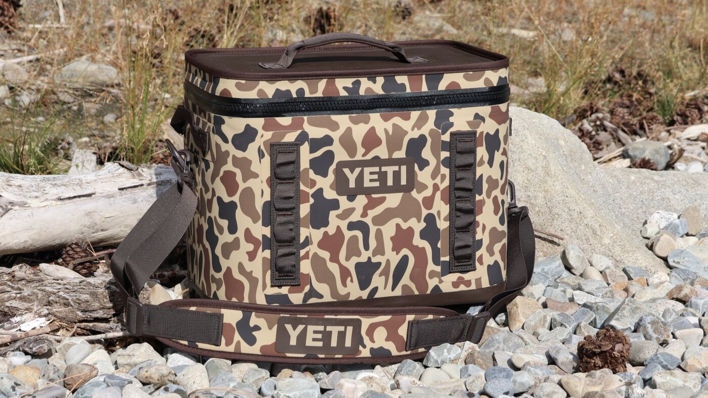 A YETI Hopper Flip 28 Soft Cooler on a rocky lake shore.